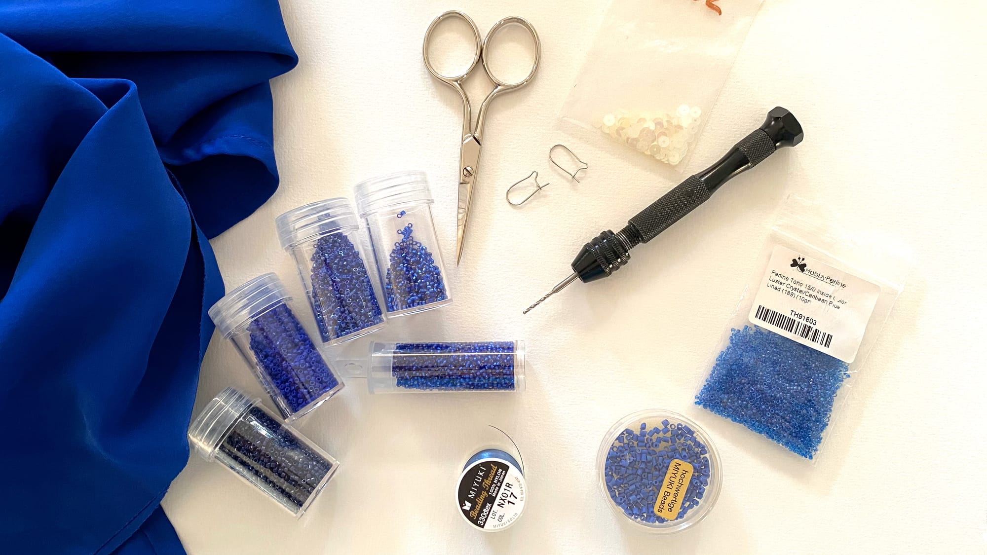 Materials used to create these earrings: organza fabric, 7 types of various blue beads, transparent sequins, beading thread, scissors, and earring hooks.