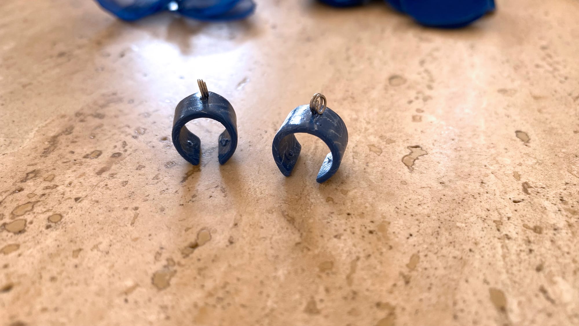 Two polymer clay elements with ball-headed pins were inserted and twisted to shape a ring on top.